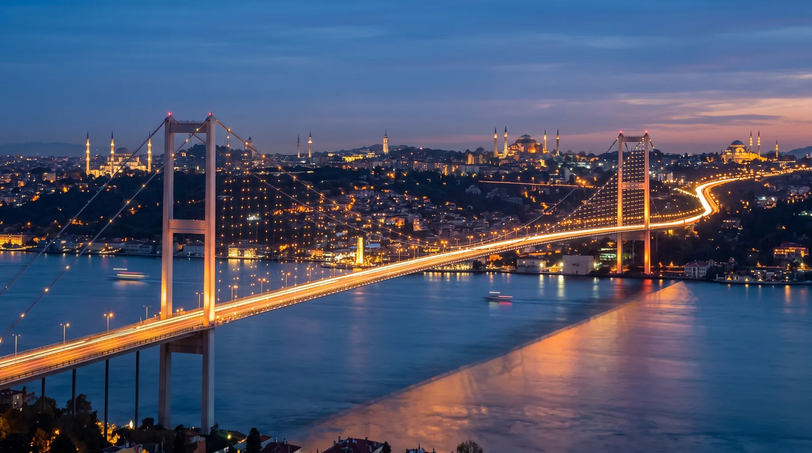 stanbul Boğazı'nda köprü geçişi — Asya ve Avrupa yakasını birleştiren asma köprü, alacakaranlıkta trafik ışık izleri